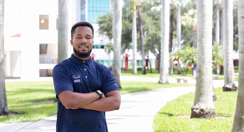 Male student standing outside next to palm trees